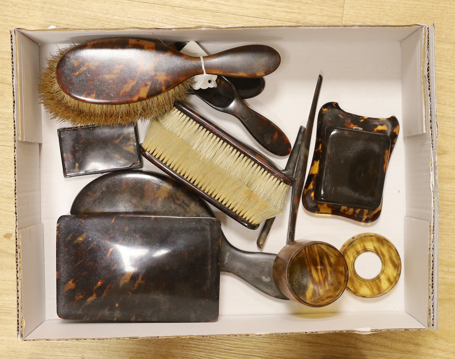 A tortoiseshell cased travelling timepiece and mixed tortoiseshell brushes, mirror, etc.